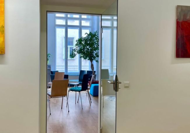 Blick vom Gang in einen hellen Raum mit Sesselkreis